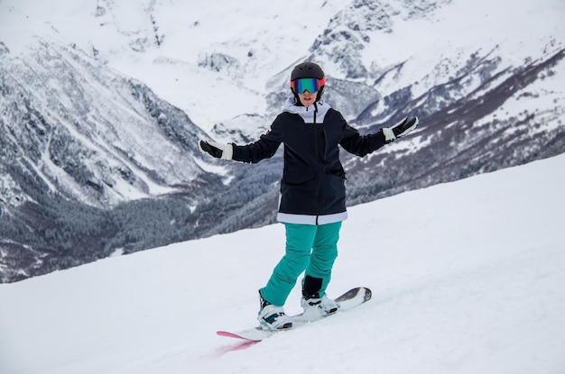 A girl on a snowboard rides down the side of the mountain