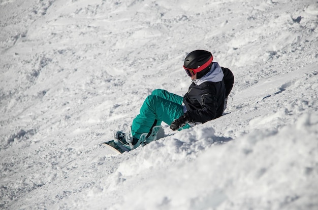 A girl on a snowboard rides down the side of the mountain