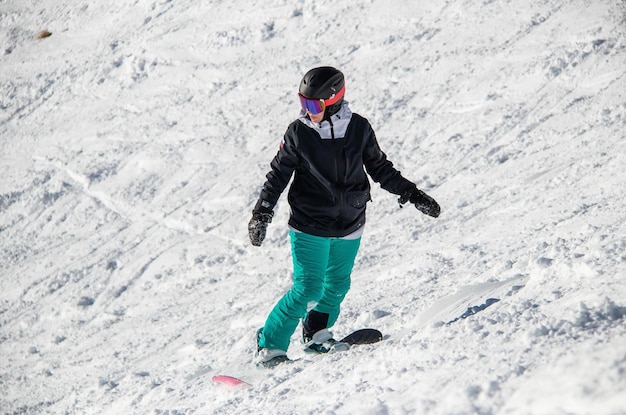 A girl on a snowboard rides down the side of the mountain