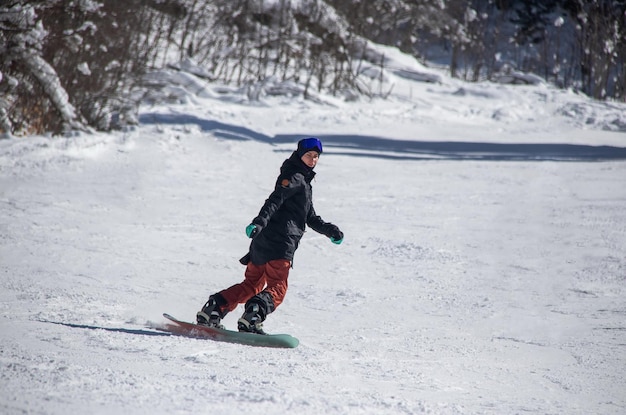 A girl on a snowboard rides down the side of the mountain