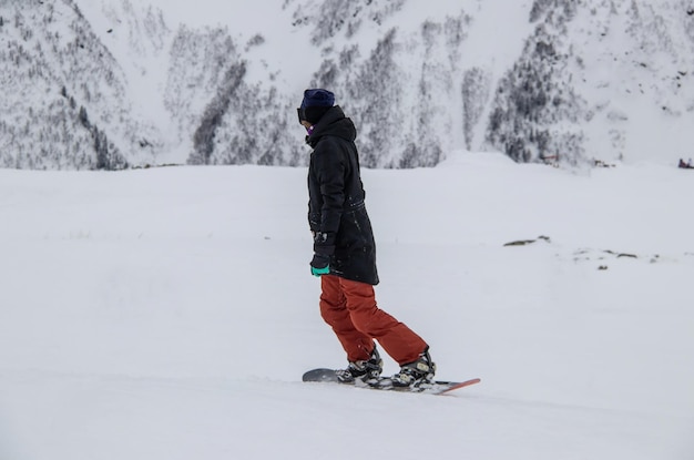 A girl on a snowboard rides down the side of the mountain