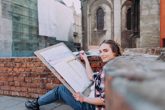 Photo girl spends leisure drawing pictures on a city street.