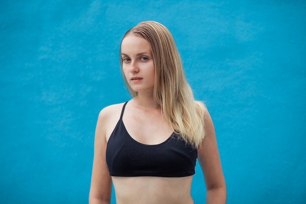 Girl in sporty black top on blue wall