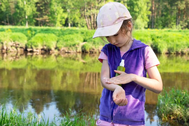 Photo girl sprays mosquito spray on the skin in nature that bite her hands and feet protection from insect bites repellent safe for children outdoor recreation against allergies summer time