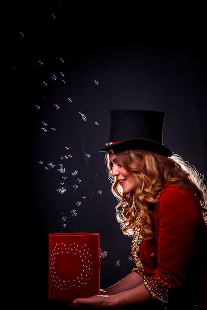 Photo girl in stage costume and top hat on her head. female magician, an illusionist in theatrical clothes