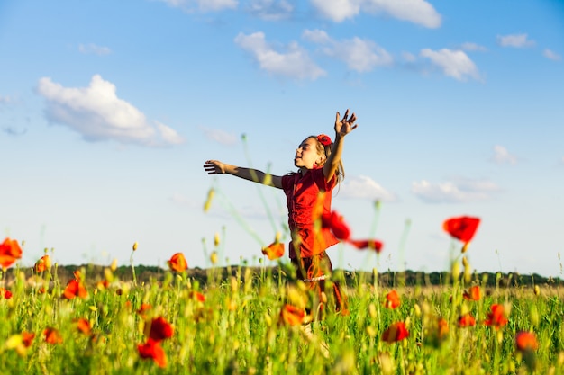 Girl stand with arms outstretched in the poppies field and enjoy the nature