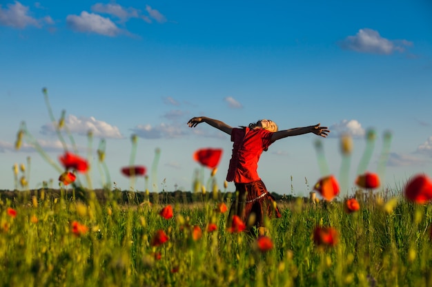 Girl stand with arms outstretched in the poppies field and enjoy the nature