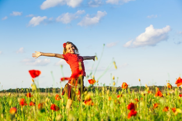 Girl stand with arms outstretched in the poppies field and enjoy the nature