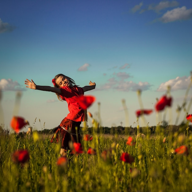 Girl stand with arms outstretched in the poppies field and enjoy the nature