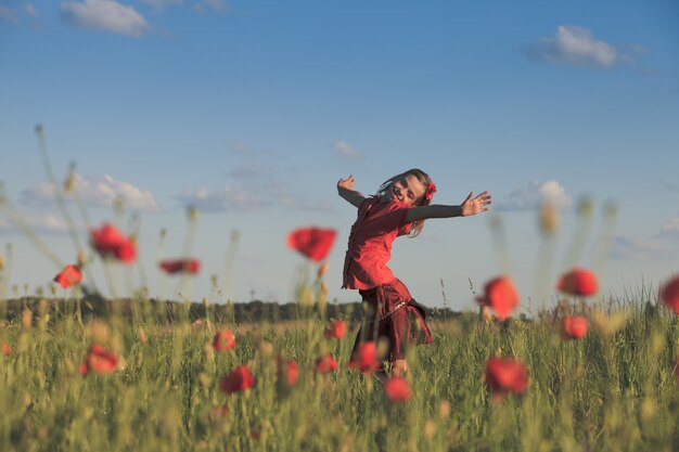 Girl stand with arms outstretched in the poppies field and enjoy the nature