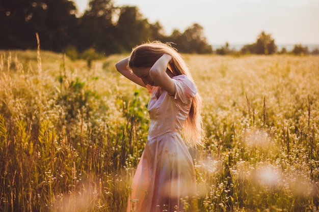 Girl standing in the field in a pink dress