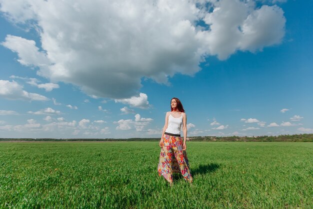 Photo girl standing in a green field of blue sky with clouds copy space