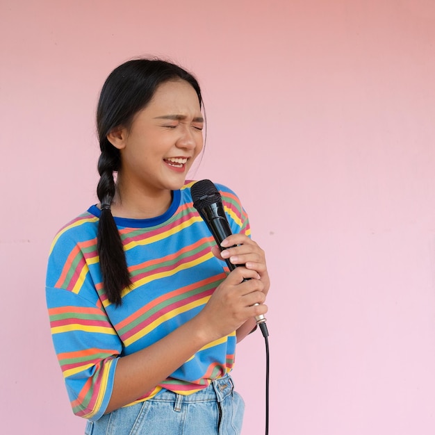 The girl standing and singing music on pink background