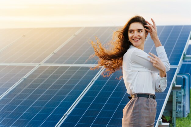 Girl standing next to solar panel rows during sunset