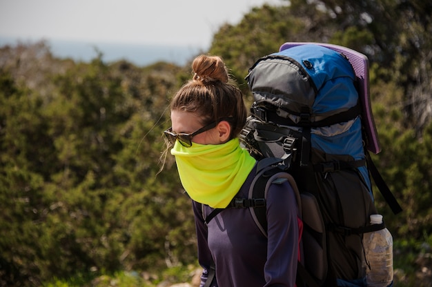 Girl standing with a hiking backpack and special mask from dust