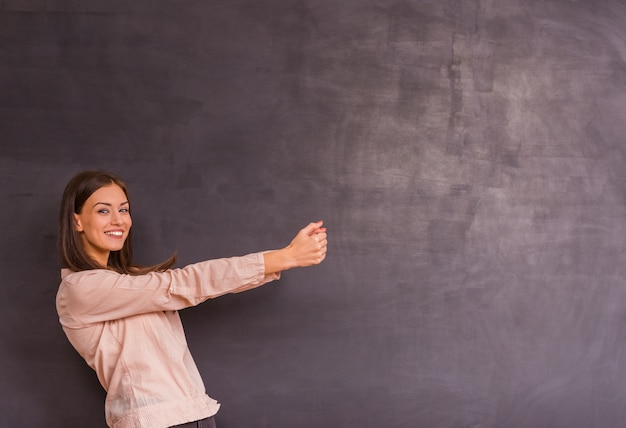 Girl stands on a gray background and pulls a hand to space.