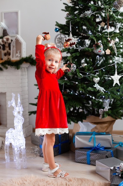 A girl stands near the Christmas tree with gifts