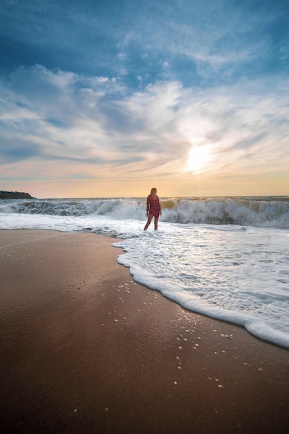 Girl during a storm on the beach in the waves