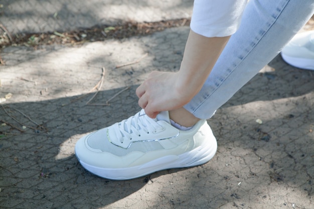 The girl straightens the laces on the shoes in the park