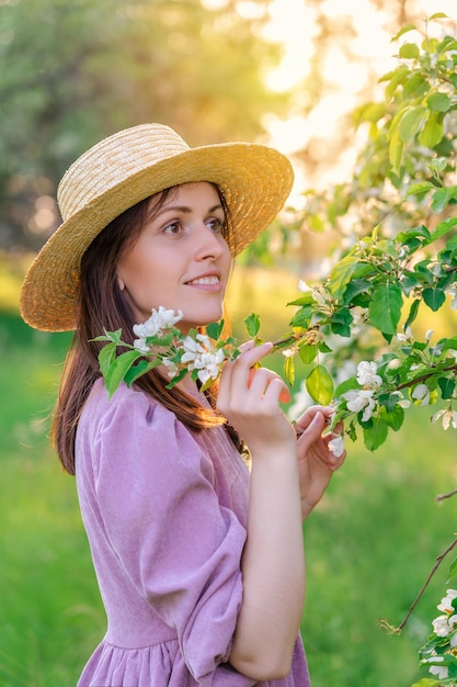 A girl in a straw hat poses in an apple orchard