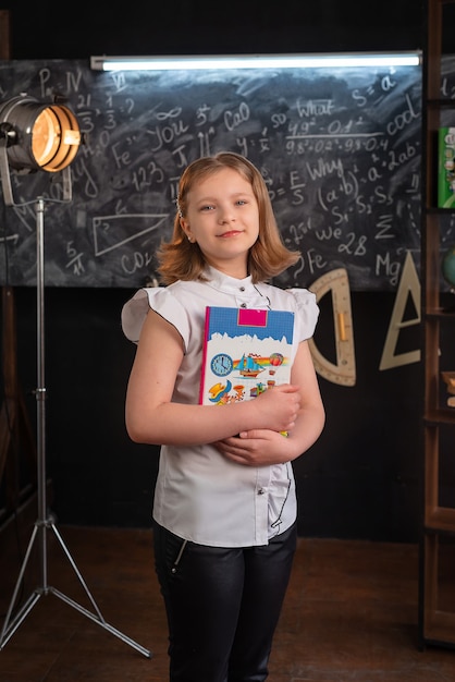 A girl in strict clothes stands at a school blackboard with inscriptions