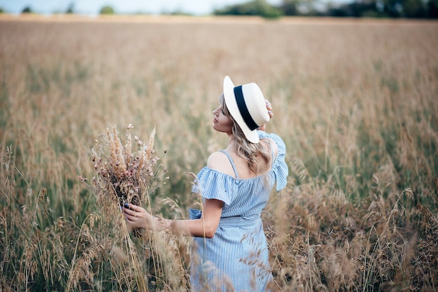 Girl in a striped dress with hat on her head in a field