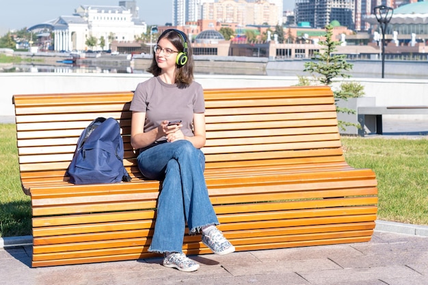 Girl student watching an online video lesson from a mobile phone on a bench A teenager girl listens to music