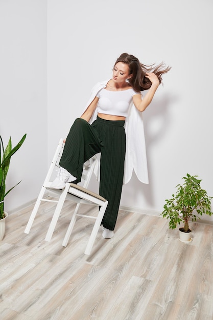 Girl in stylish clothes with a chair for the photographer