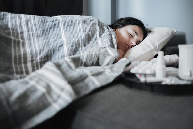 Girl suffering from a seasonal cold lies in bed Antiviral drugs on a tray