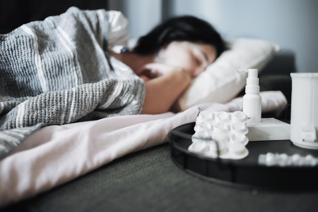 Girl suffering from a seasonal cold lies in bed Antiviral drugs on a tray