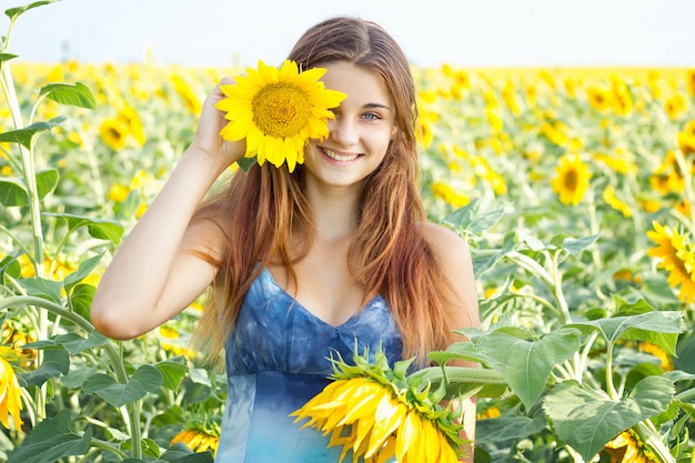 Girl in sunflower field, emotional girl, beauty joyful teenage girl with sunflower, sun rays, sun rays, glowing sun. Illuminated.