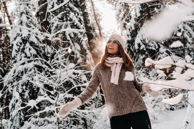 A girl in a sweater and glasses in winter in a snow-covered forest