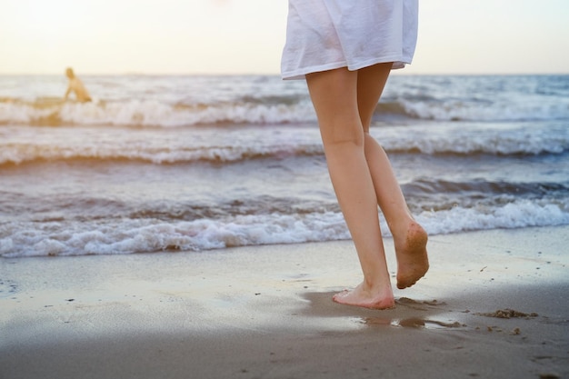 Girl in a swimsuit is playing on the beach with a sea wave jumping running having fun