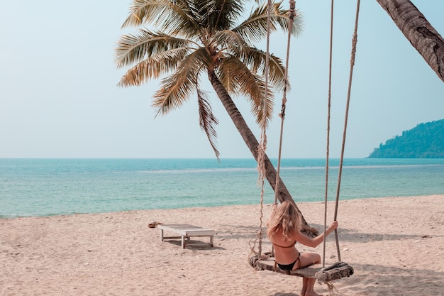 Girl swinging on a swing by the sea