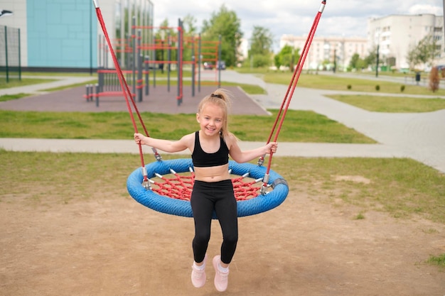 A girl swings on round swing on a playground