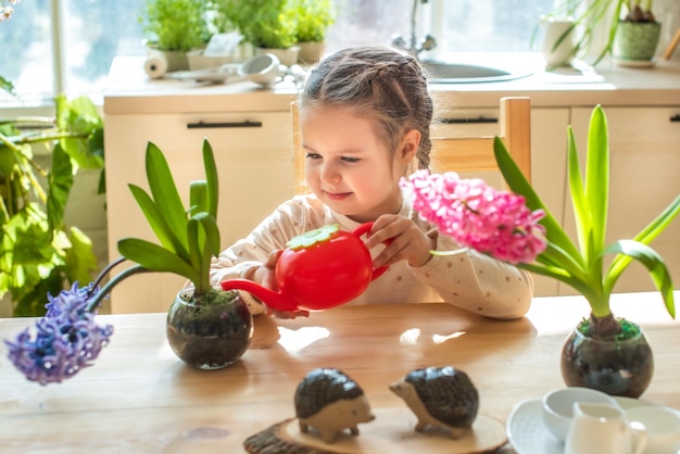 Girl take care of plants in pots Child is watering the houseplant from a watering can