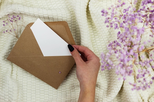 The girl takes out a Blank white sheet from a craft envelope. Layout of invitation and greeting card.