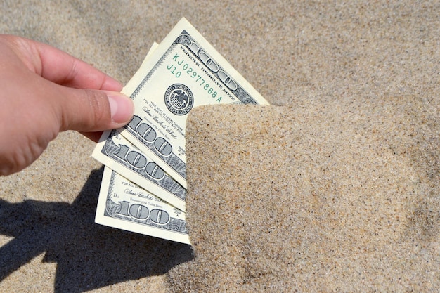 A girl takes out from the sand money notes of three hundred dollars