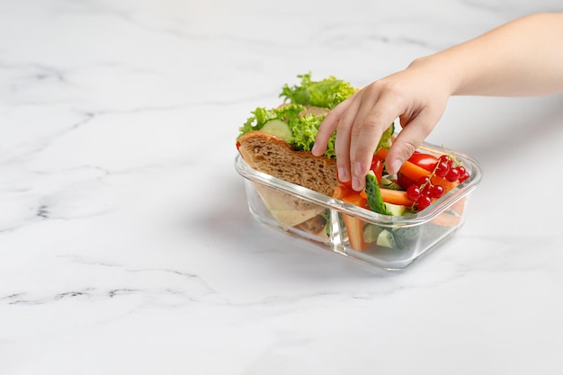 Girl taking reaching a sandwich toasts vegetables snack Container glass box with take away food