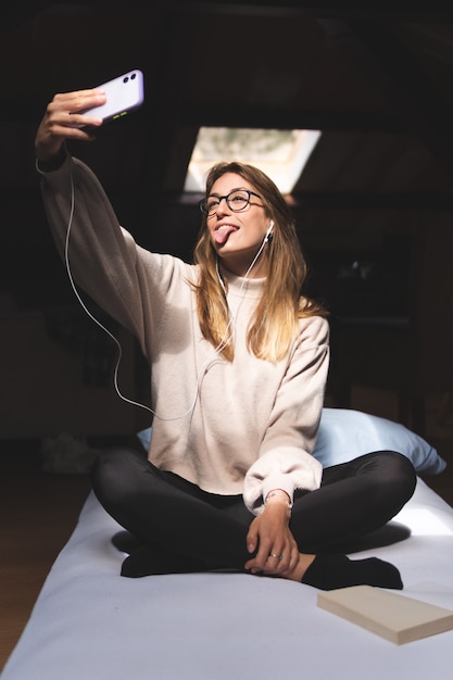 girl taking a selfie with her tongue out in bed