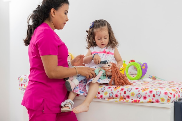 Girl taking the temperature of her wrist while she is in consultation with her pediatrician doctor