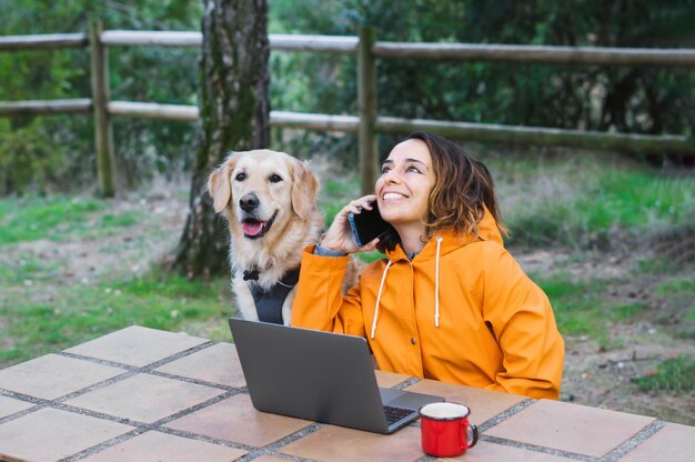 Girl talking on the phone next to computer and dog