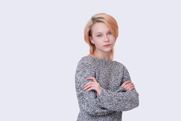 Girl teenager in a closed position looks into the frame isolated on a light background