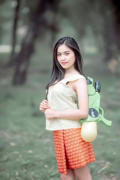 Girl in Thai traditional dress standing holding a water gun Ready to go out to play in the water during Songkran festival