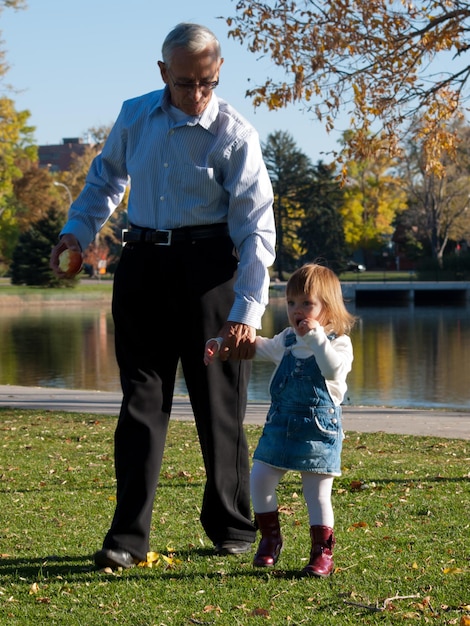 Girl toddler with grandfather in autumn park.