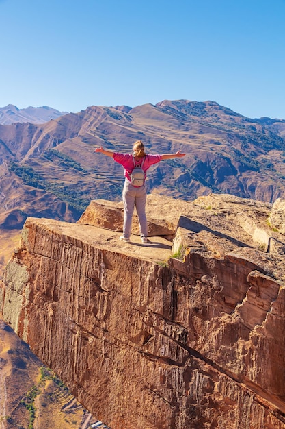 Girl tourist on an extreme ledge in the rock Troll tongue