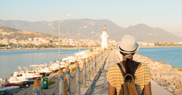 Girl tourist in a hat with a backpack on the background of the embankment with