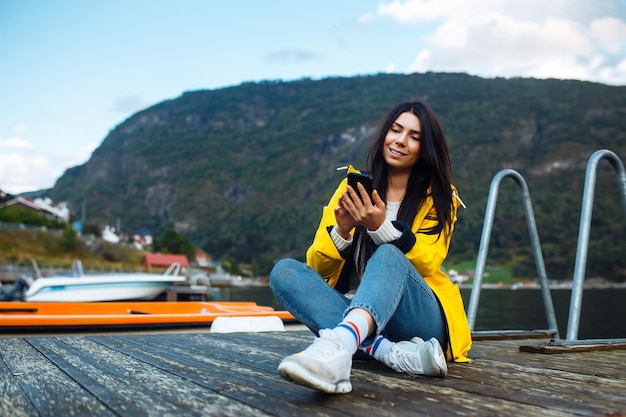 The girl tourist takes a photo on the phone by the lake in Norway Young woman takes selfie