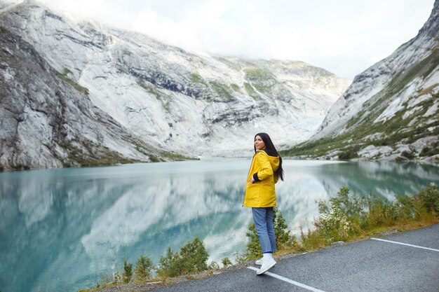 Photo girl tourist in yellow jacket posing on the lake in norway active woman relaxing in the norway