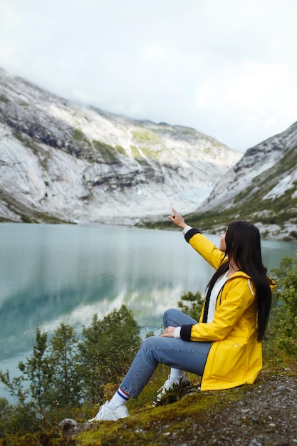 Girl tourist in yellow jacket posing on the lake in Norway Active woman relaxing in the Norway